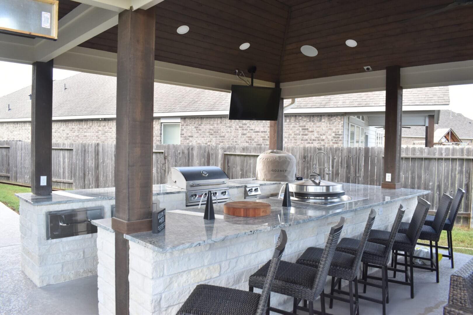 A large outdoor kitchen with an entertainment center.