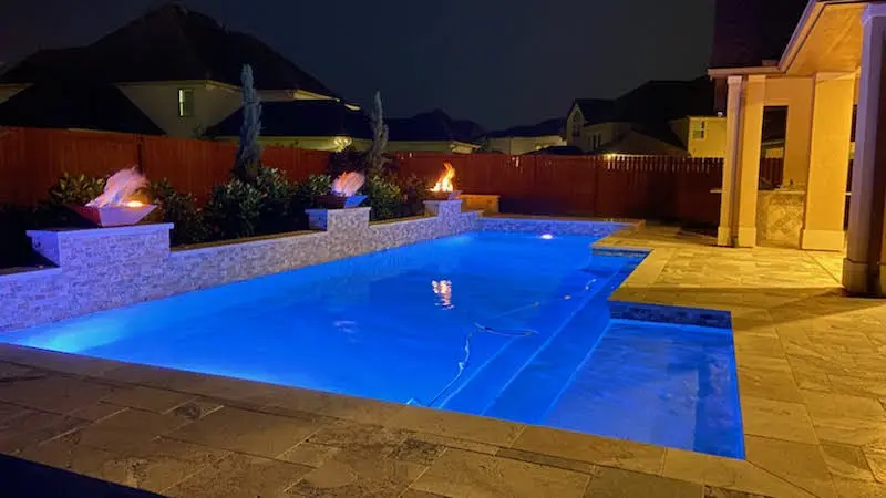 A pool with blue lights and fire pit.